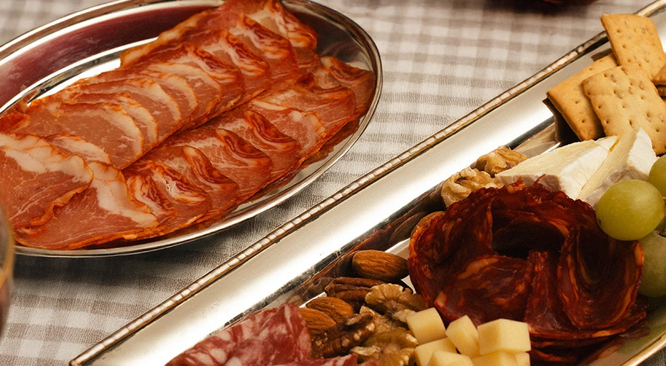 Tapas Legado Ibérico: mesa con plato de lomo ibérico y bandeja con chorizo, queso, uvas y picos.